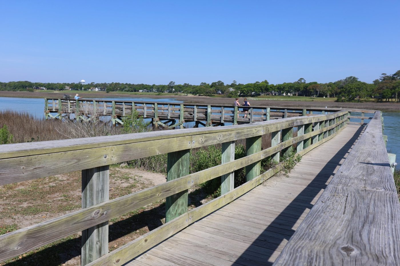 Long wooden fishing pier extending over the waterway at Cherry Grove Park