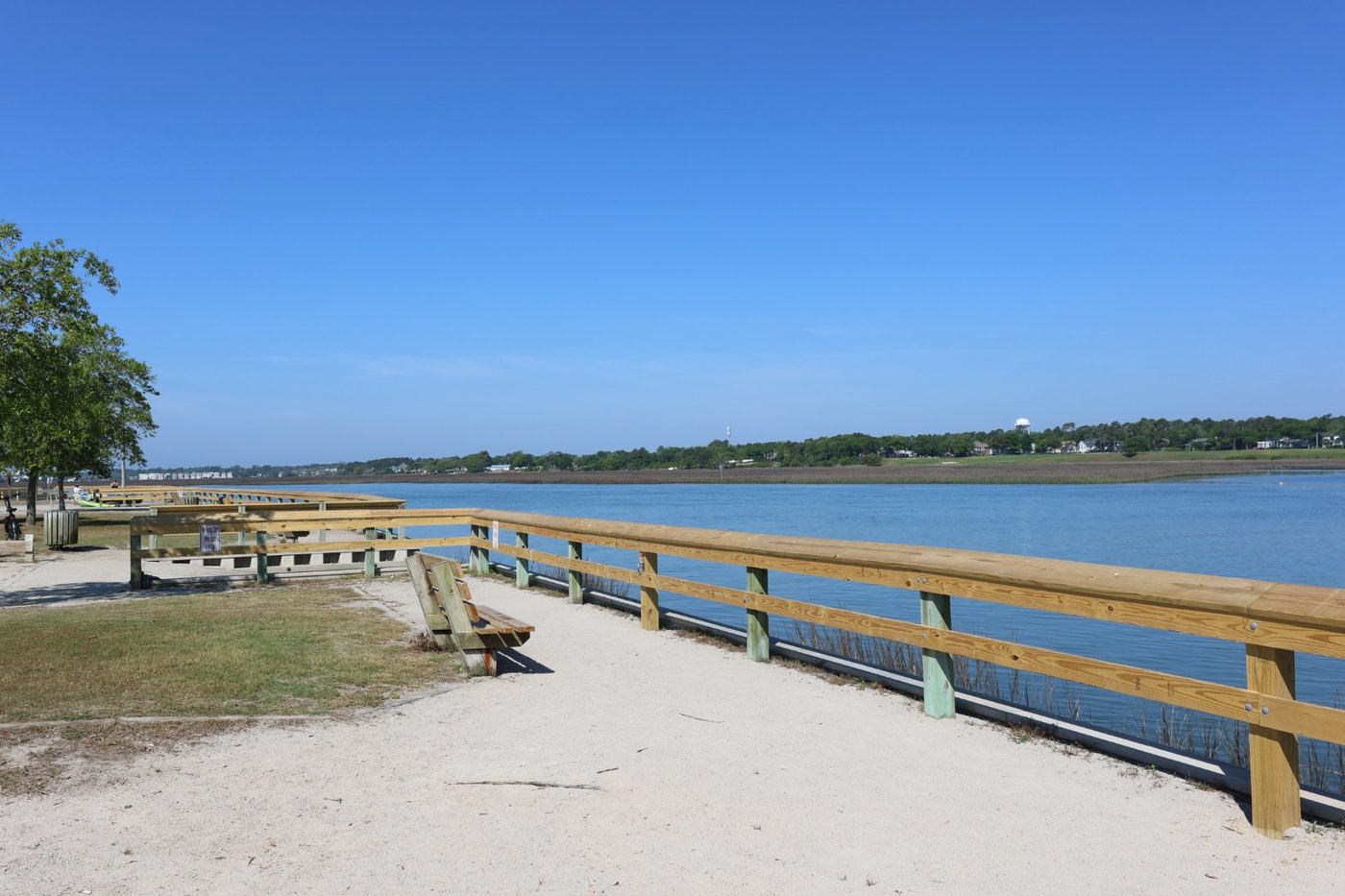 Waterfront walkway with wooden railing and bench at Cherry Grove Park